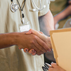 Handsome male Hispanic young adult medical professional shaking hands with doctor. Happy young adult Hispanic male nurse shakes hand with doctor during a medical conference.